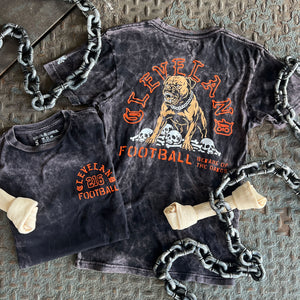 Black t-shirt with orange graphic design featuring a dog and text, displayed on a textured surface with chains.